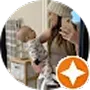 A woman wearing a knit beanie taking a mirror selfie while holding a baby